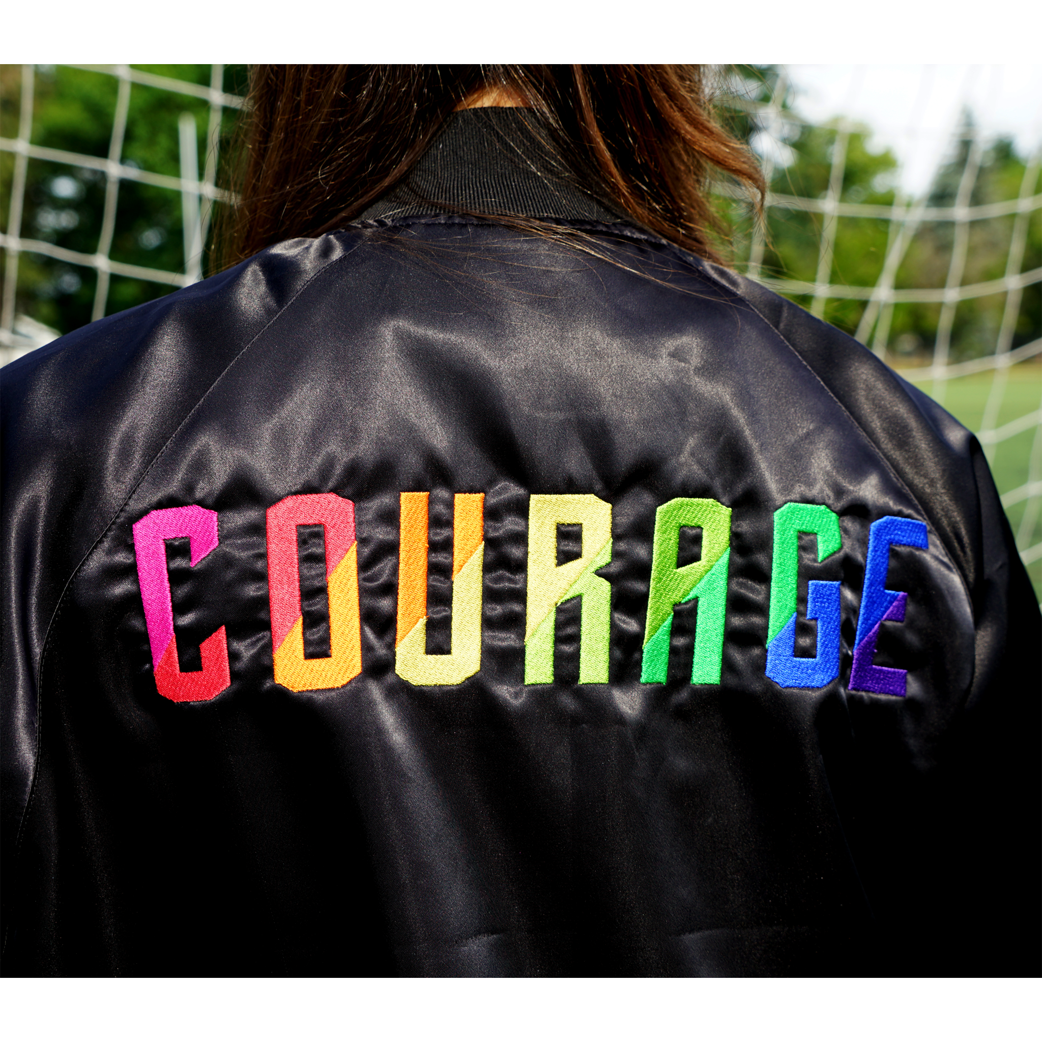 A closeup of the back of the jacket with the Courage ext embroidered in rainbow colors.