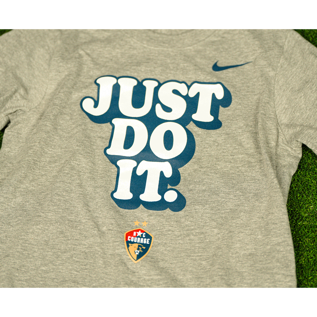 A closeup of a charcoal gray Nike t-shirt with the 'Just Do It' slogan and the NC Courage logo on the front.