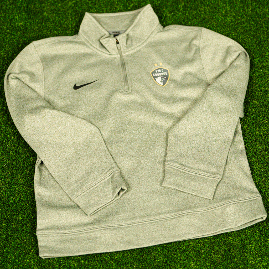 A gray Nike Therma 1/4 zip youth Pullover with the NC Courage logo on the chest.