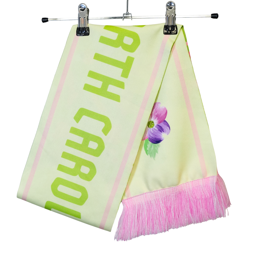 Folded scarf on a hanger. Pale yellow scarf with pink fringe and North Carolina in green