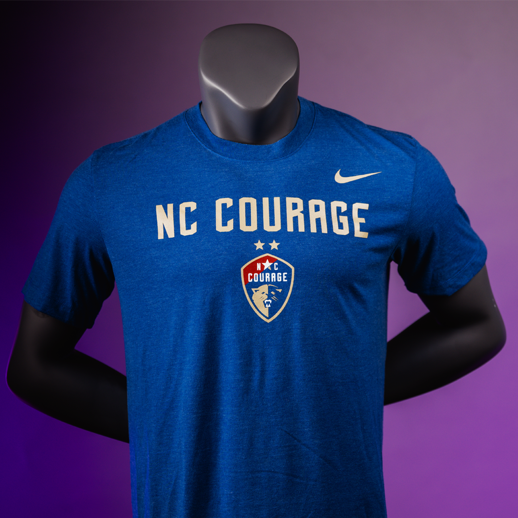 A mannequin wearing a blue t-shirt with 'NC COURAGE' written in white and the NC Courage logo in white and red.