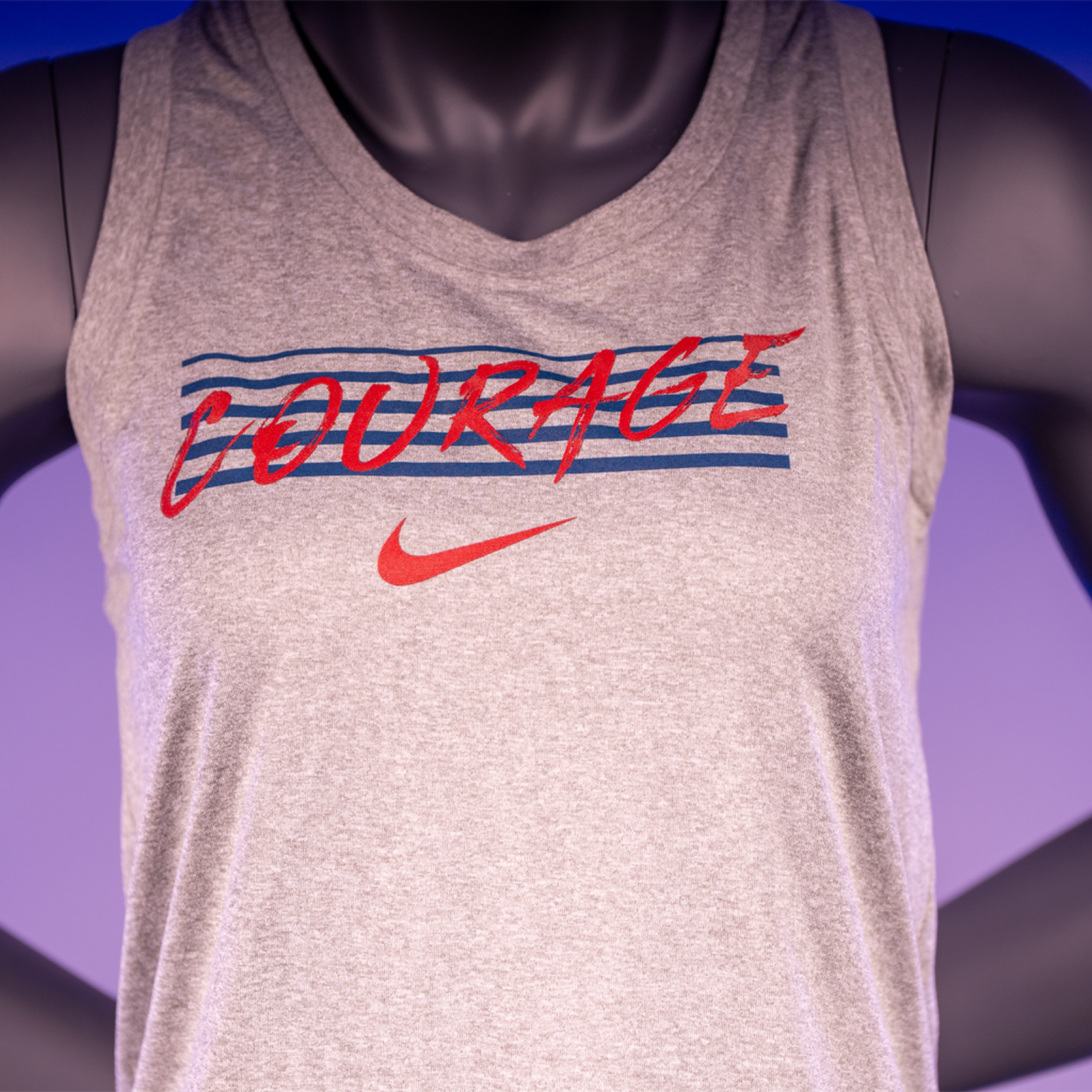 A close up of a mannequin wearing a gray tank top with the text 'COURAGE' and the Nike logo.