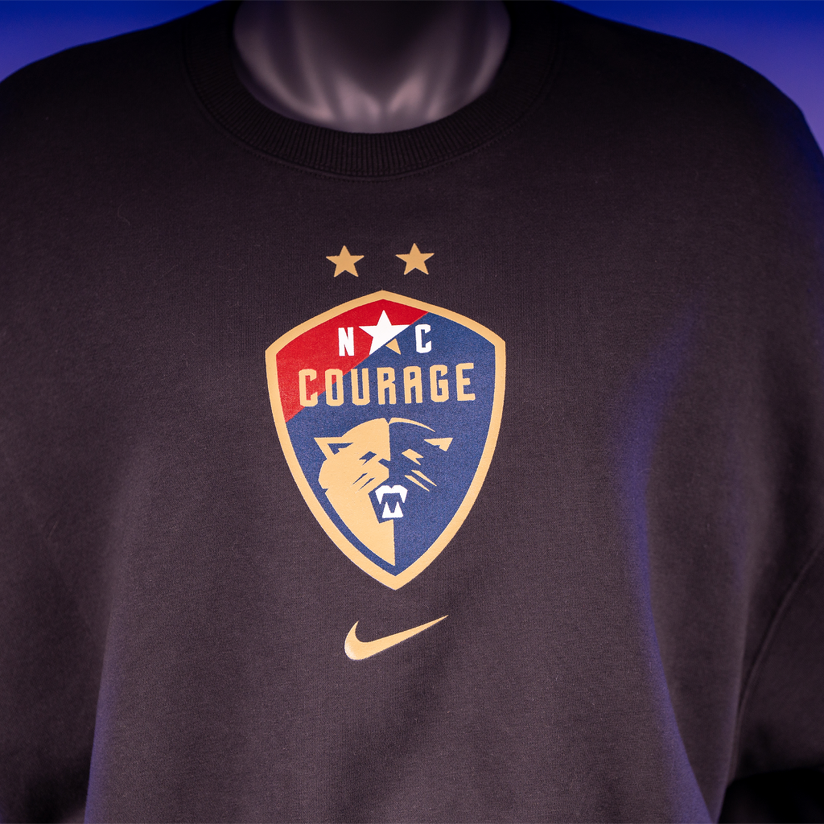 A close up of a black cropped oversized crewneck sweatshirt with the NC Courage logo on the front.
