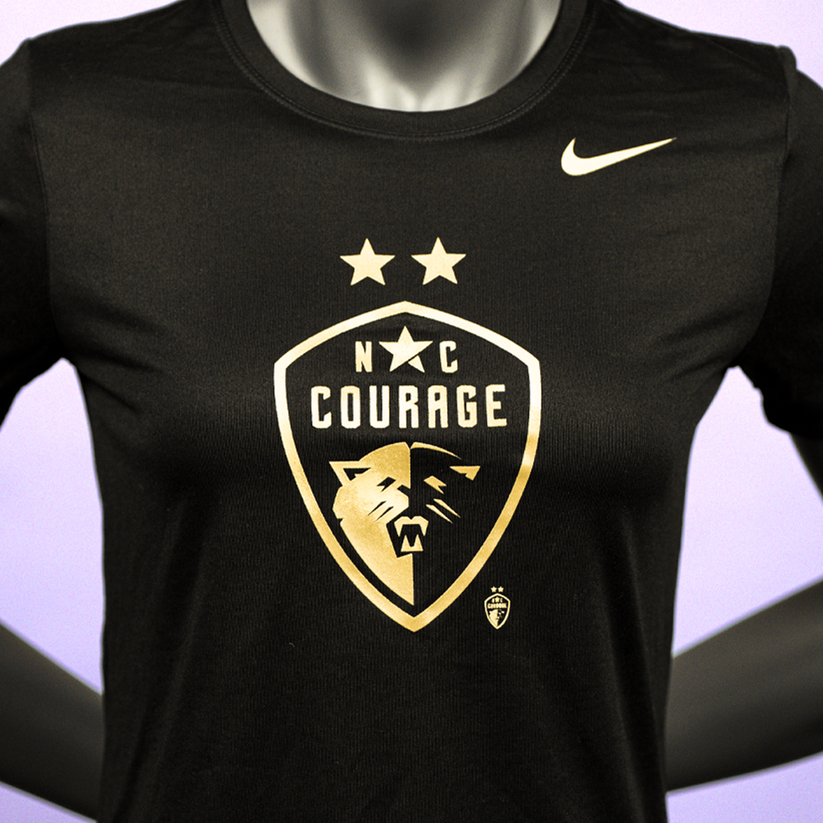 A close up of a mannequin wearing a black t-shirt with the 'NC Courage' logo in gold and black, featuring Nike branding as well.