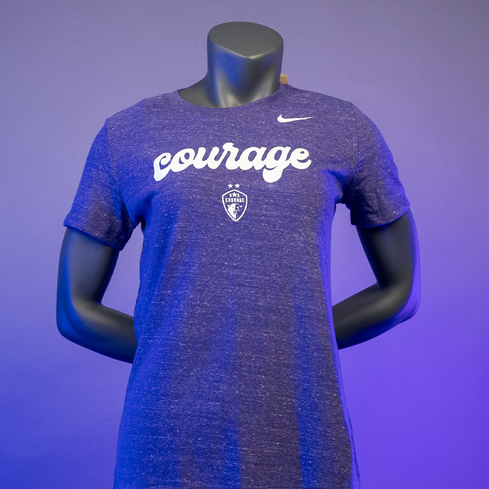 A mannequin wearing an orchid purple NC Courage women's varsity tee with the brand logo and the word 'courage' printed across the front.