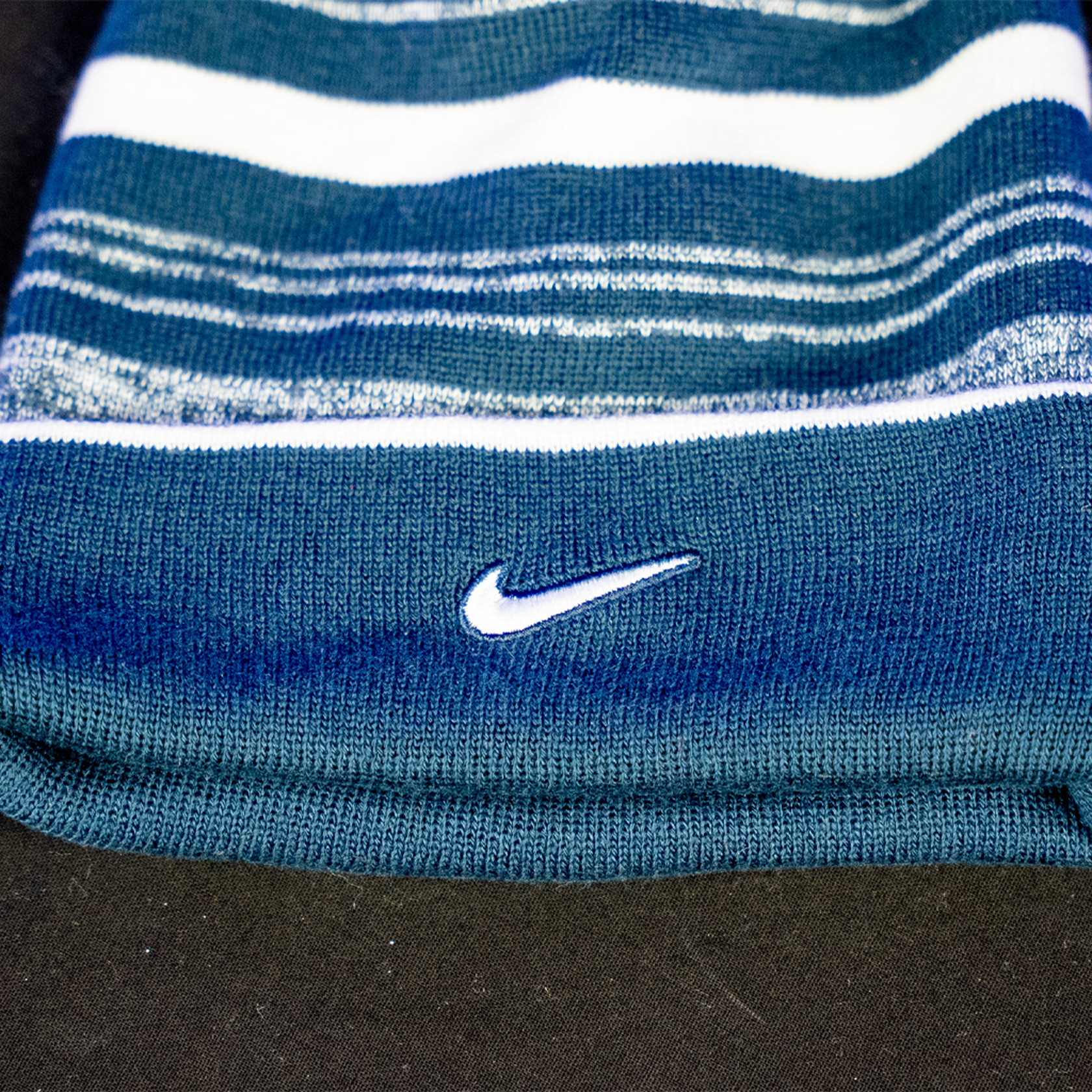 A navy and white striped beanie, featuring the Nike logo.