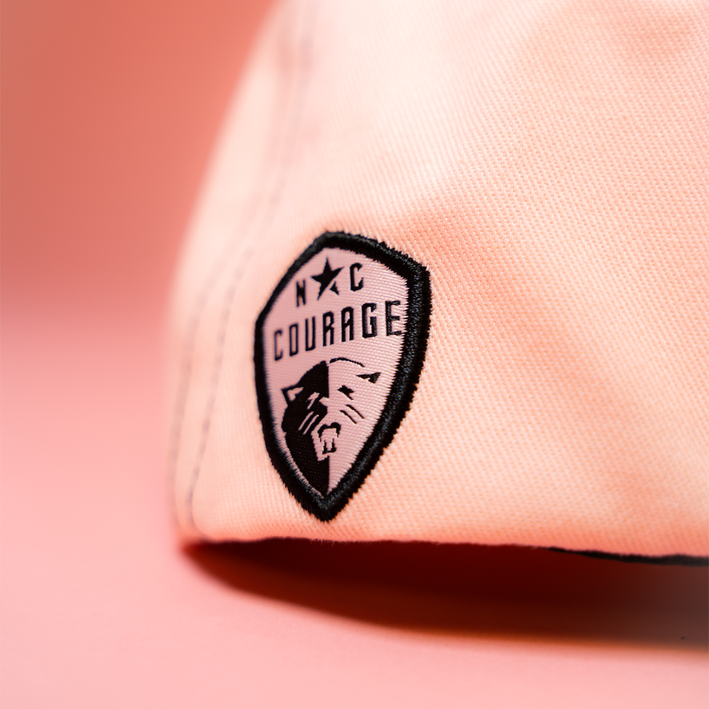 Black North Carolina Courage logo on a pink fabric background
