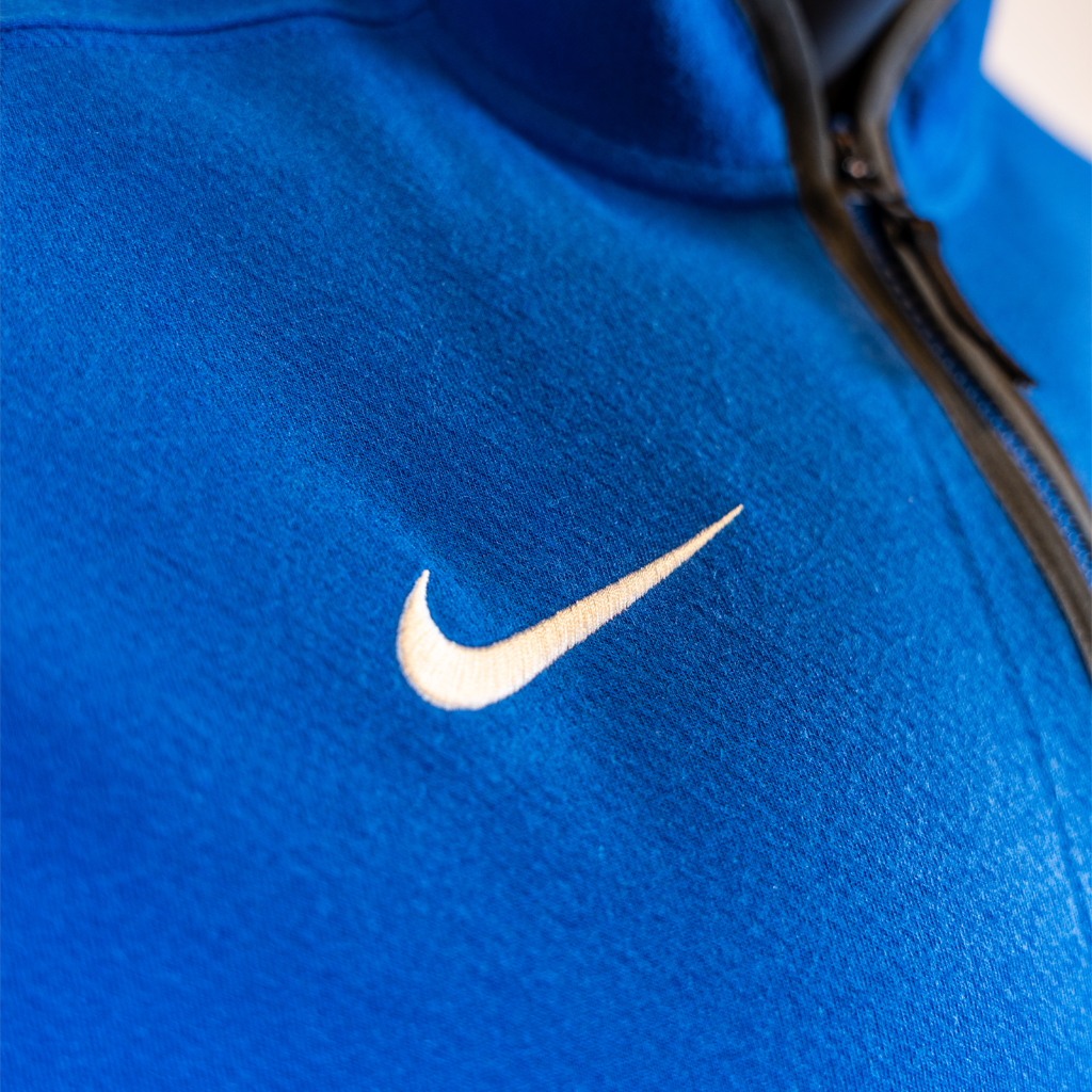 Close-up of a blue jacket with a white Nike logo on the chest.