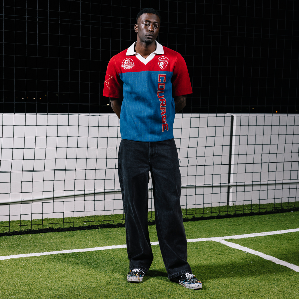 Person wearing a red and blue sports jersey with branding on a sports field.