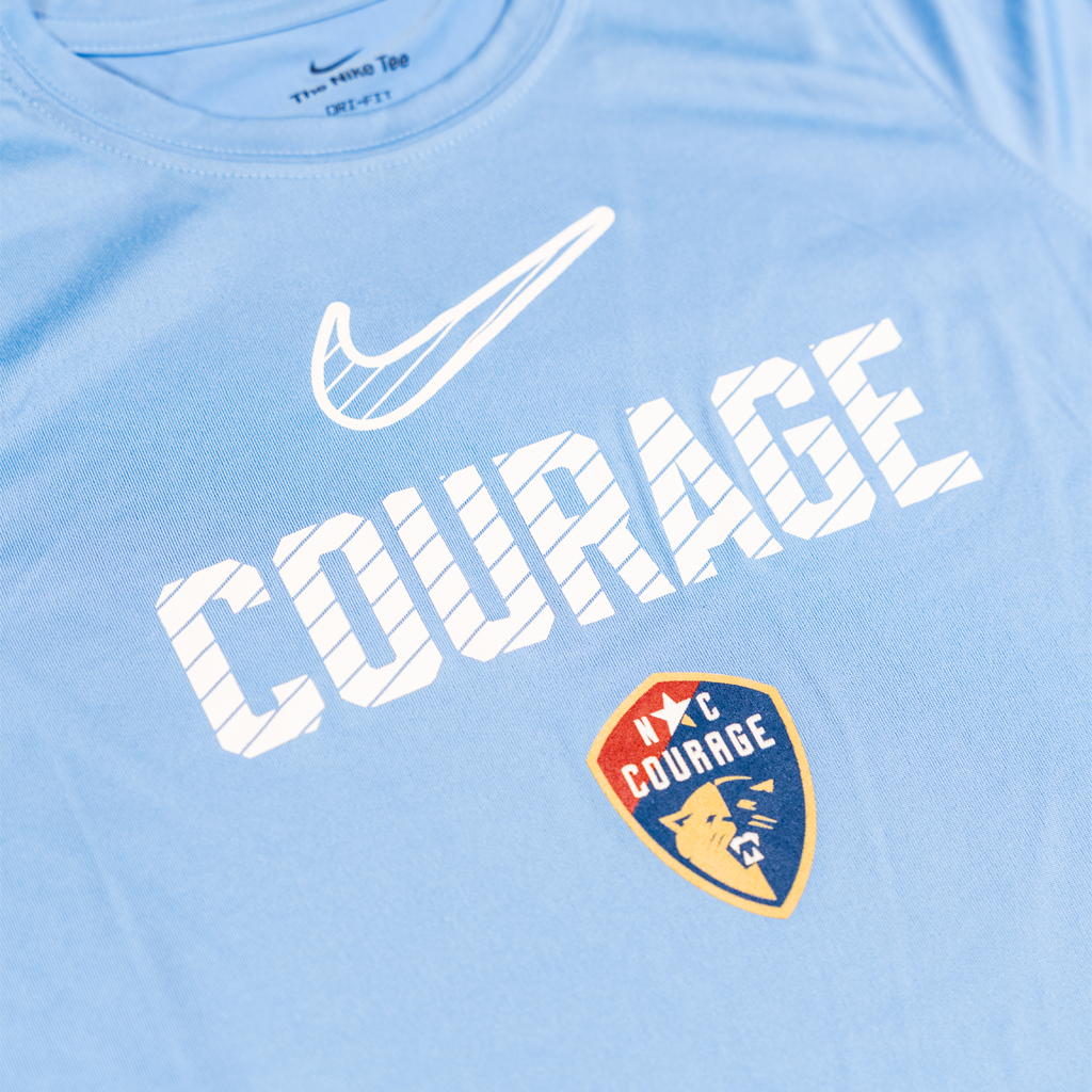 Close-up of the light blue t-shirt with 'Courage' text and Nike logo on a plain background