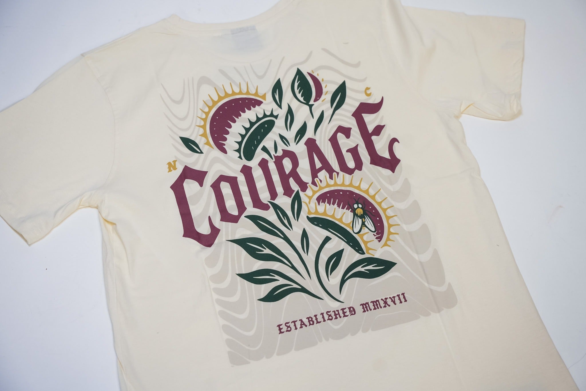 Beige t-shirt with 'Courage' graphic design on a white background