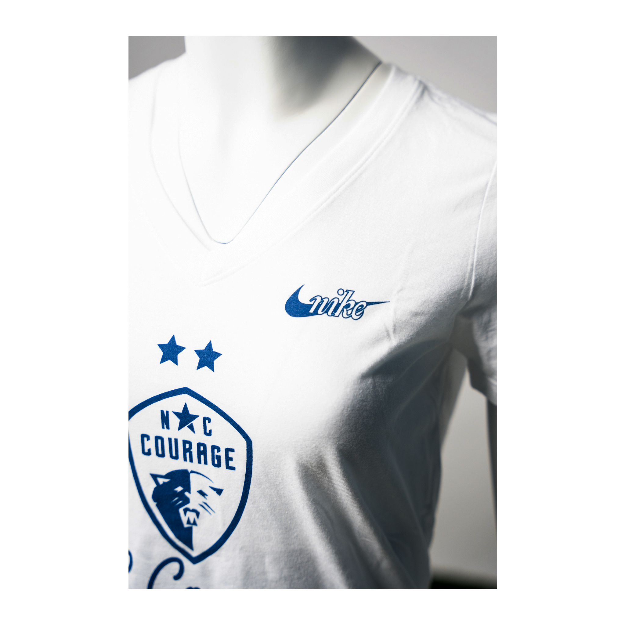 A white Nike V-neck t-shirt with the NC Courage logo and Nike swoosh in navy blue.