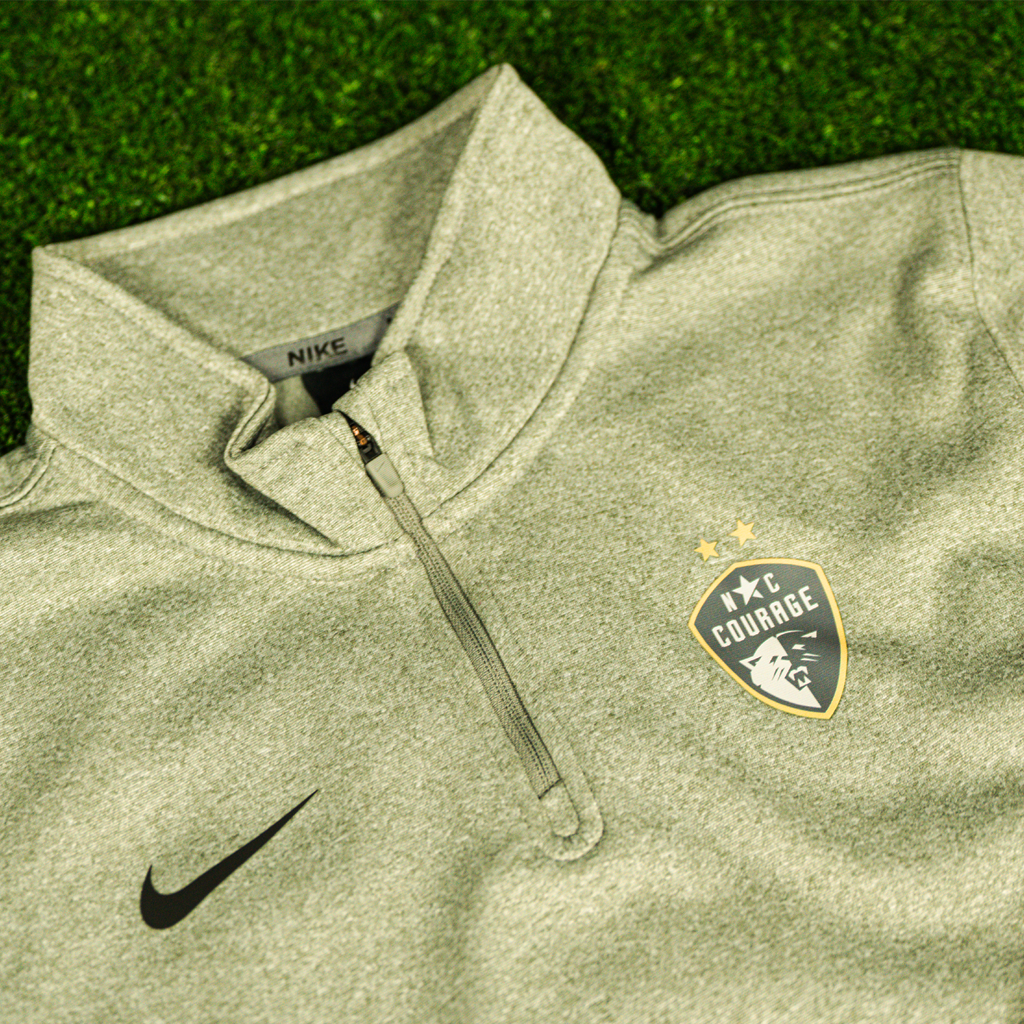A close up of a gray Nike Therma 1/4 zip youth Pullover with the NC Courage logo on the chest.