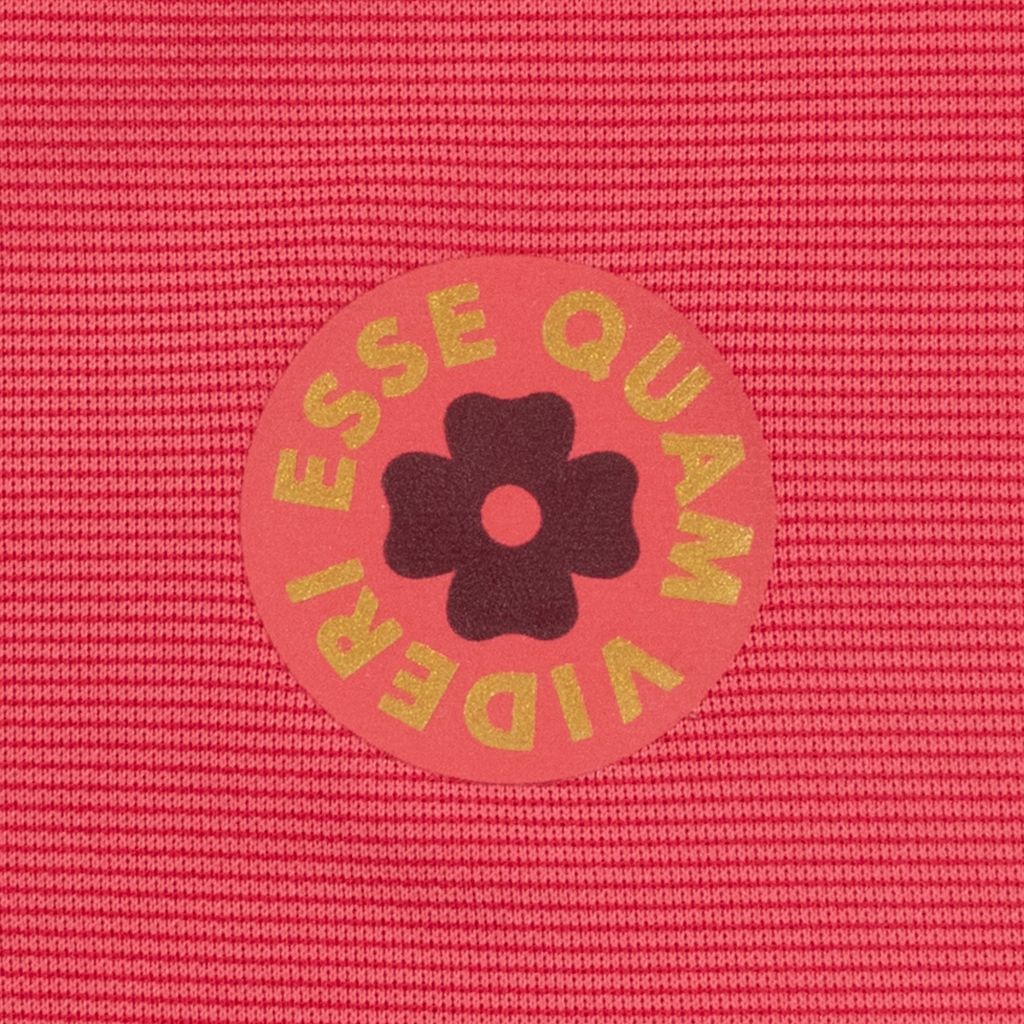 Pink textured fabric with a circular logo featuring a flower and text.