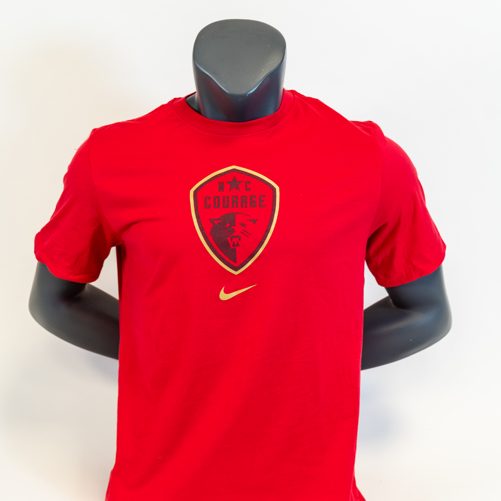 A pink Nike t-shirt with the NC Courage crest printed on the front, displayed on a mannequin.