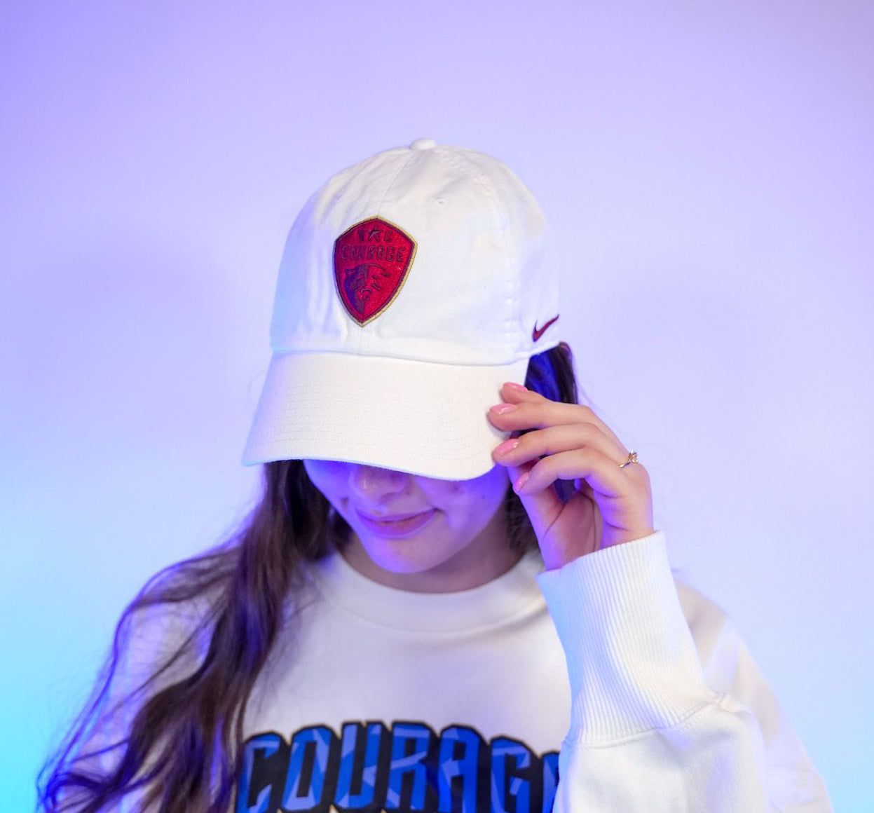 Person wearing a white Nike cap with a red NC Courage logo. 