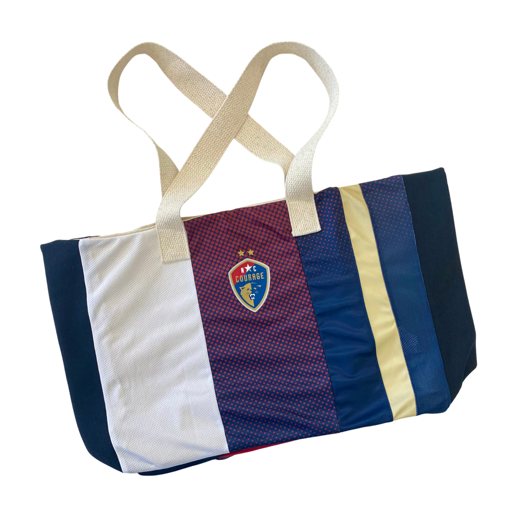 A beach bag with horizontal stripes in various colors, including blue, white, and red, with the NC Courage logo on the front.