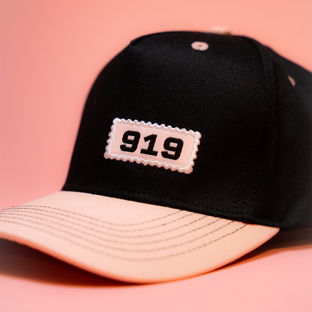 Black cap with '919' patch on a pink background