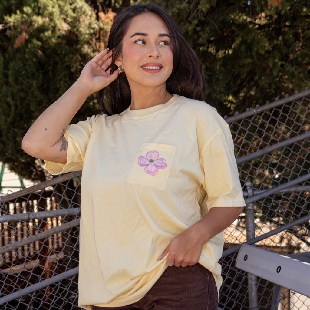 Model wearing Yellow t-shirt featuring embroidered pink flower on the chest pocket and the "Official League" leather logo in the bottom right 