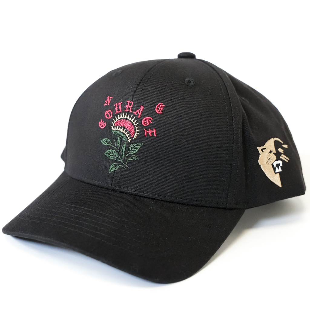 Black cap with pink and green floral design and 'Courage' text on a white background