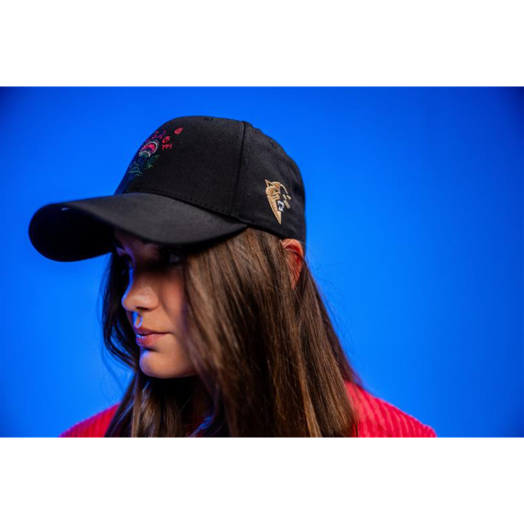 Person wearing a black cap with floral designs against a blue background