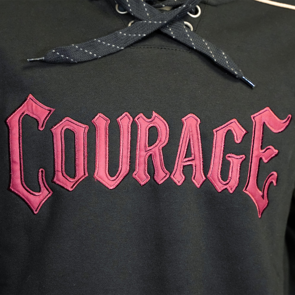 Black hoodie with pink 'Courage' text on a dark background