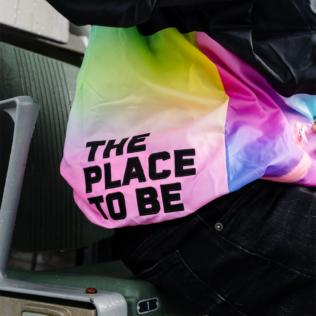 Colorful tie-dye bag with 'THE PLACE TO BE' text held by a person.