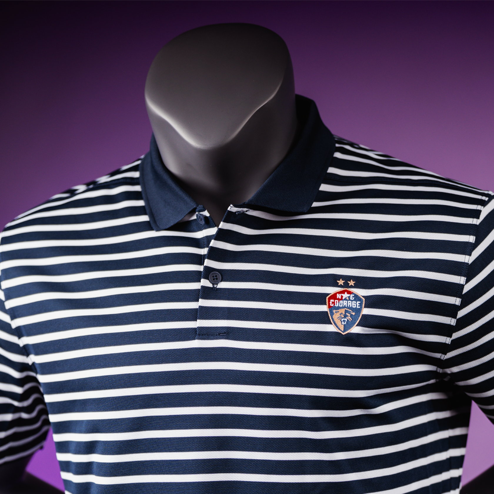A close up of a striped polo shirt displayed on a mannequin, featuring a combination of black and white stripes with a small logo on the chest.