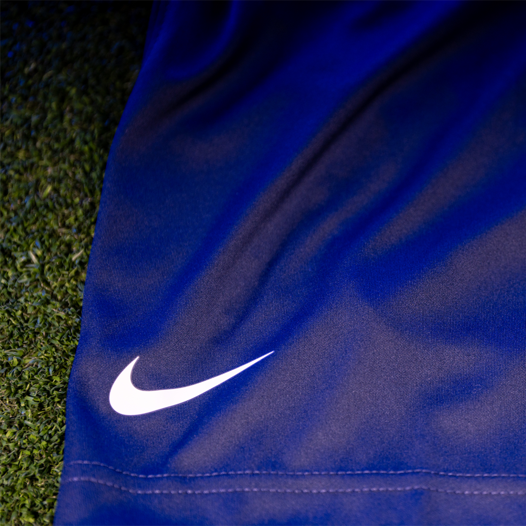 A close up of a white Nike logo on a pair of blue sports shorts.