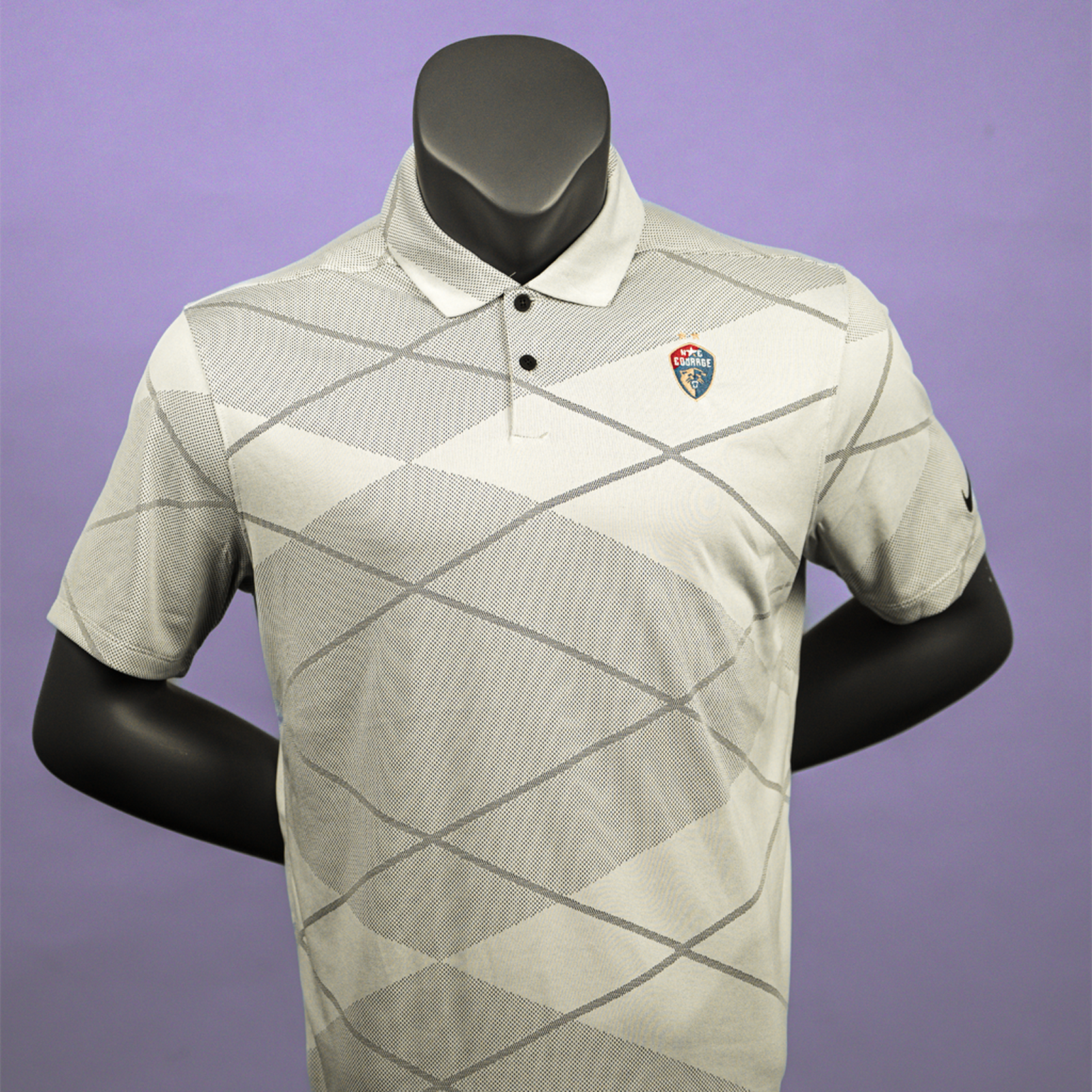 A gray jacquard pattern polo shirt with the NC Courage logo embroidered on the chest displayed on a mannequin.