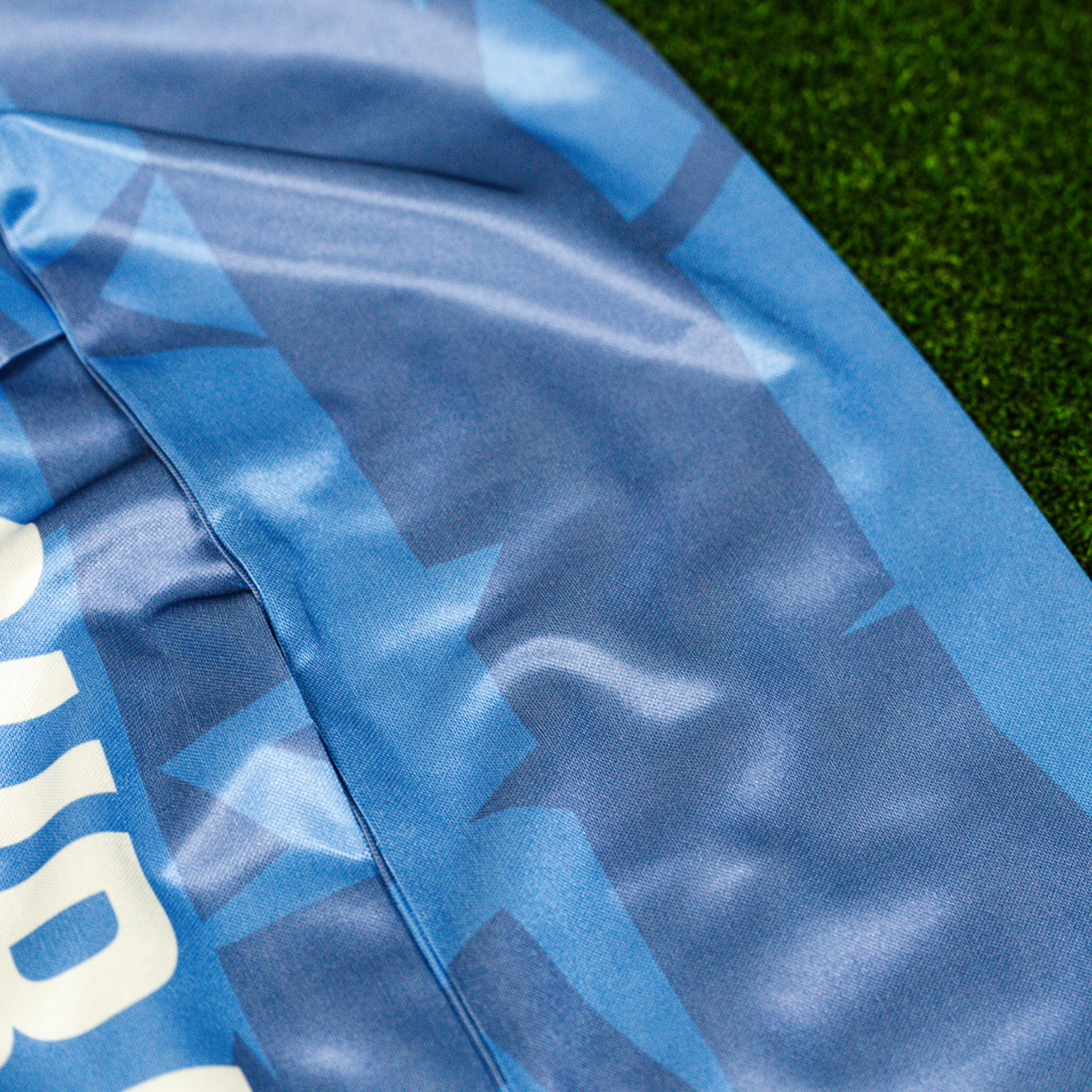 A zoom in of a purple scarf with the text 'ALL COURAGE' and the NC Courage logo, displayed on a green grass-like surface.