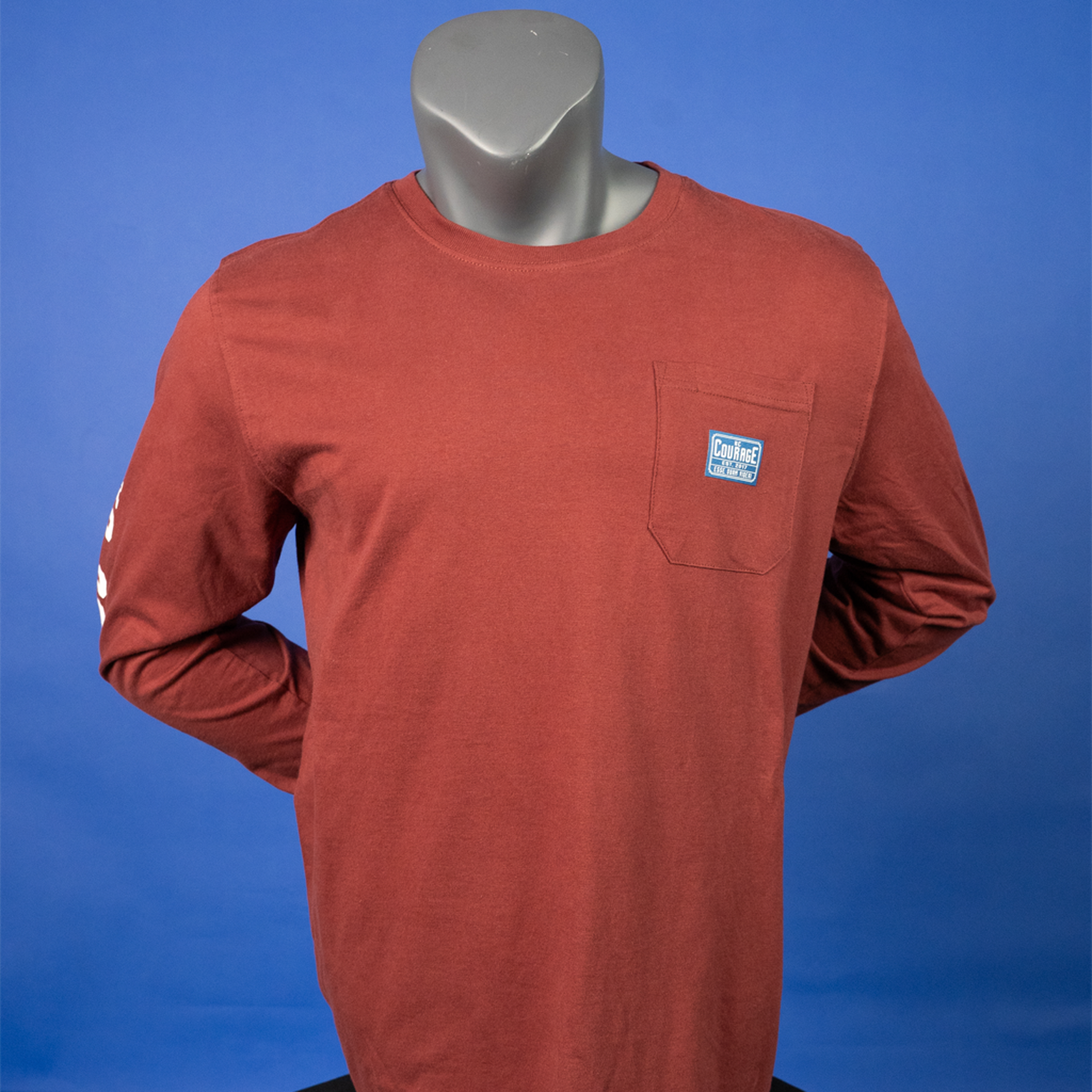 A rust-colored long sleeve t-shirt with the NC Courage logo on the chest and a white pattern on the sleeves.