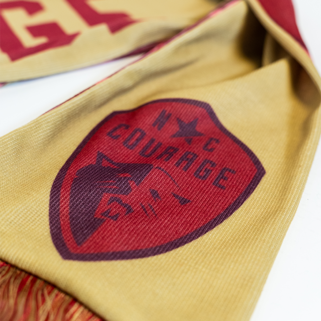 Close up of pink North Carolina Courage logo on a gold scarf