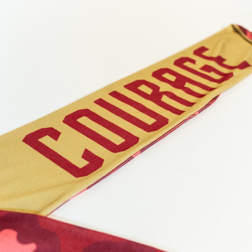 "Courage" text in pink on gold scarf