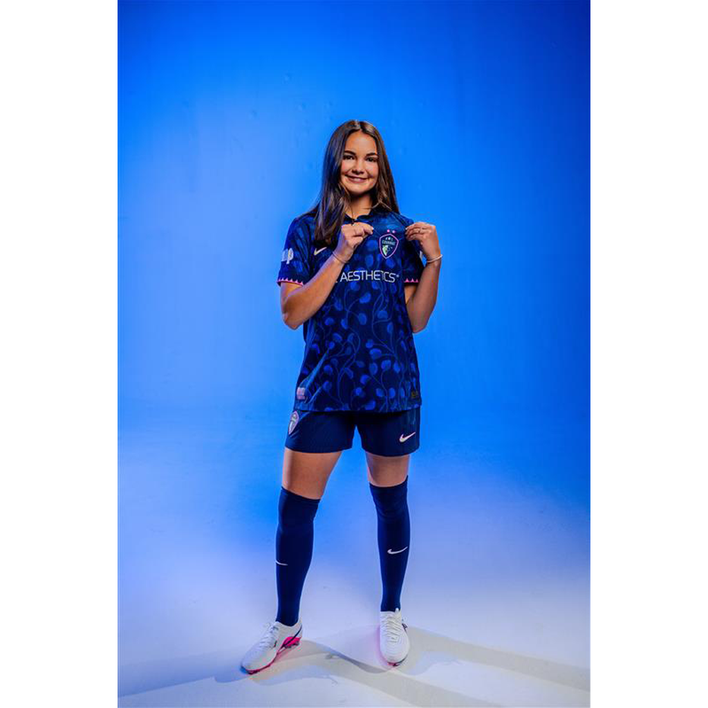 Person wearing a blue sports outfit with visible branding on a blue background