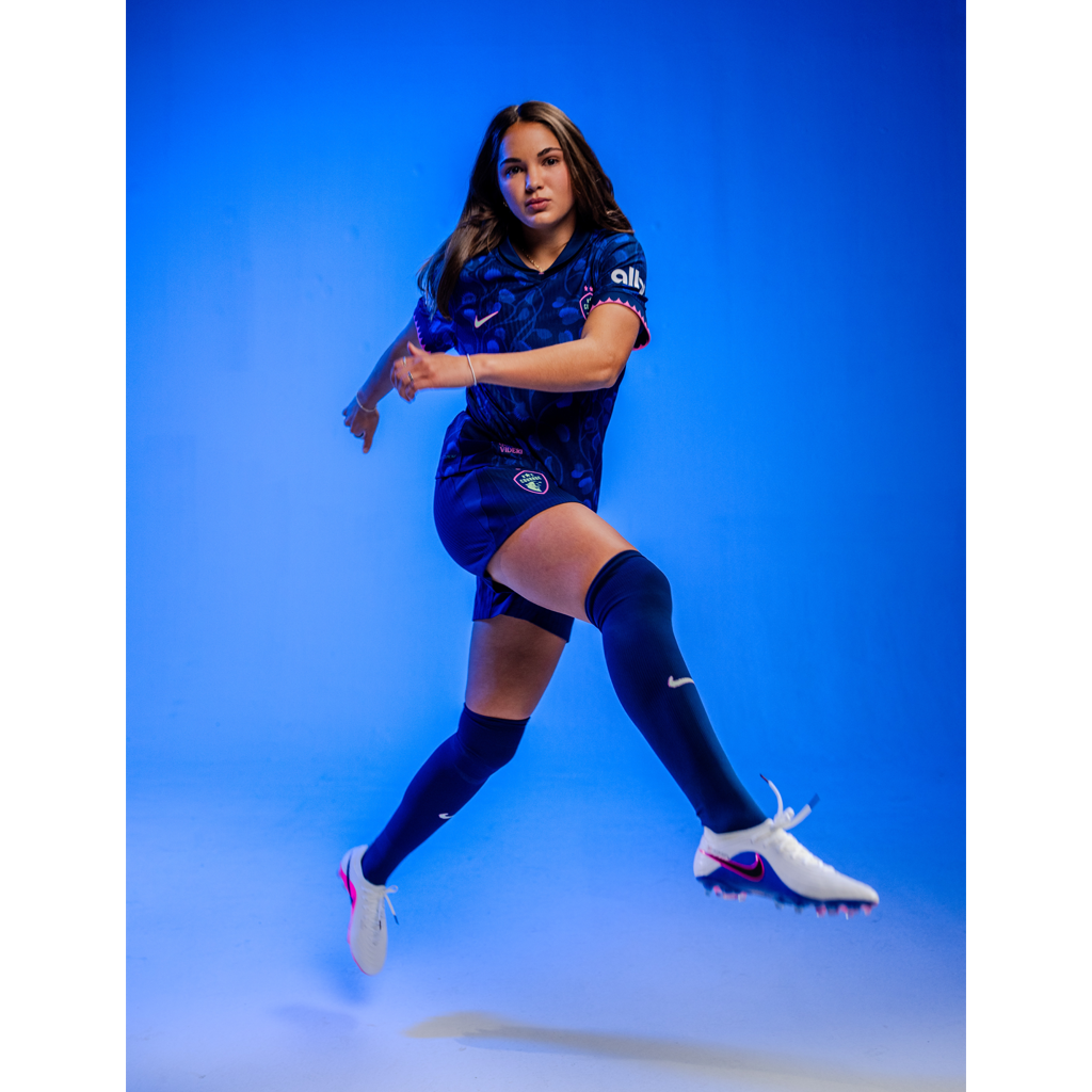 Person wearing a blue sports outfit with visible branding on a blue background