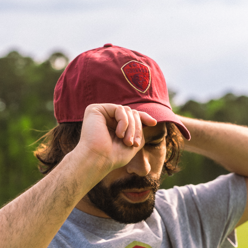 Man wearing the red baseball cap with the 'NC Courage' crest logo on the front and a visible Nike swoosh.