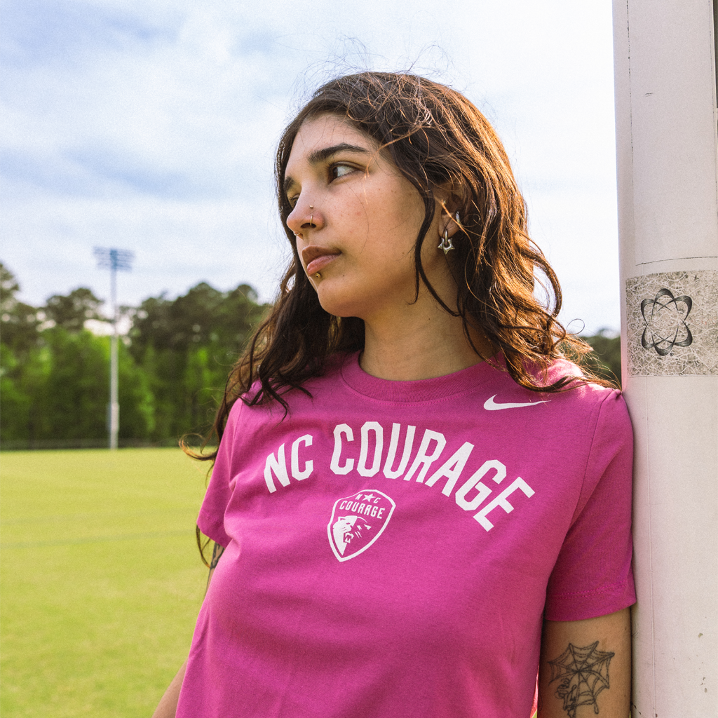 Person wearing the pink Nike Dri-FIT t-shirt with 'NC COURAGE' printed on the front over the North Carolina Courage logo