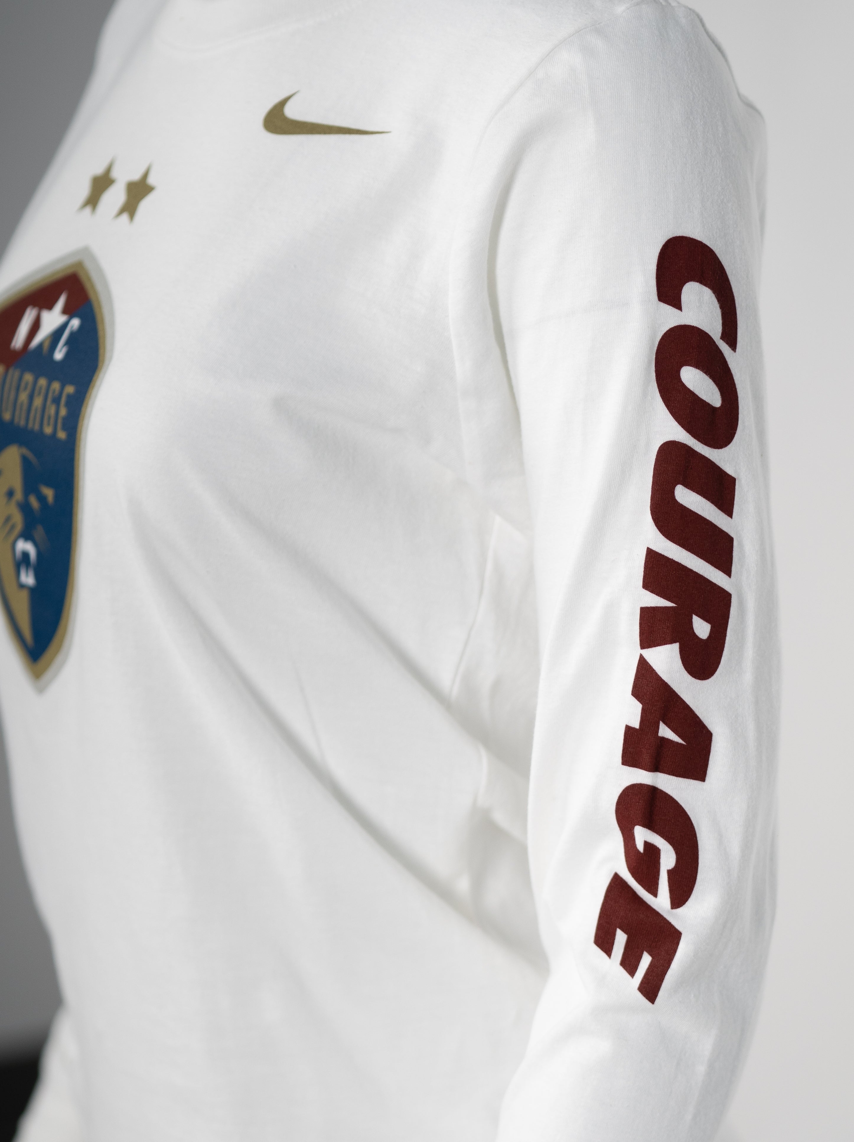 Women's white long sleeve cotton t-shirt with a sports team crest on the chest and the name 'COURAGE' down one sleeve.
